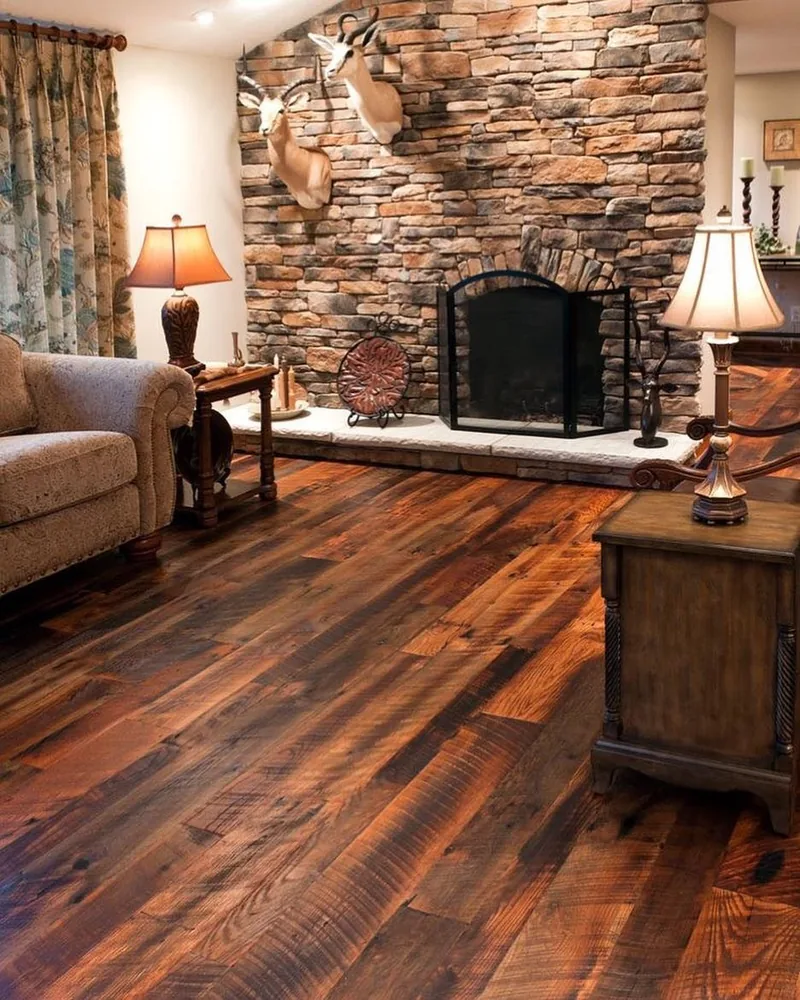 Reclaimed wide-plank floor with heavy colour variation in a room with a stone fireplace