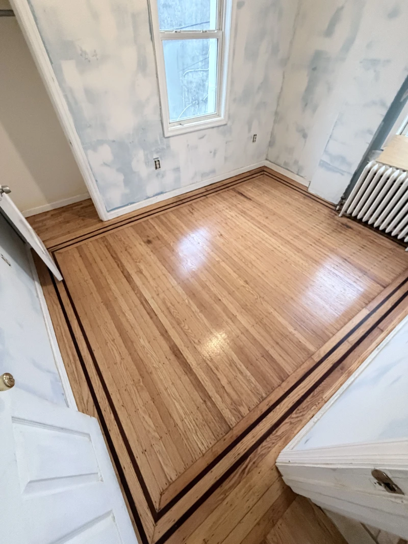 Refinished floor in a period bedroom, dark border inlay running around the edge