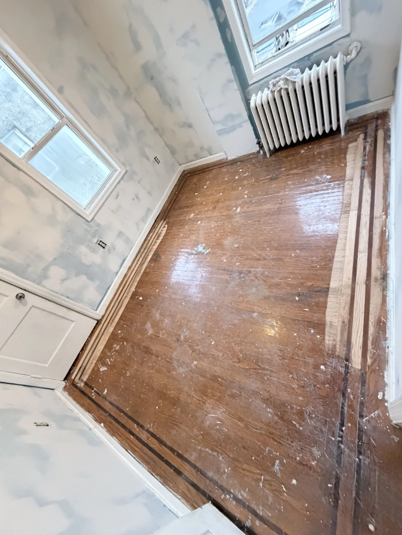 Old bedroom floor before restoration, paint spatter across the boards and a dark border inlay
