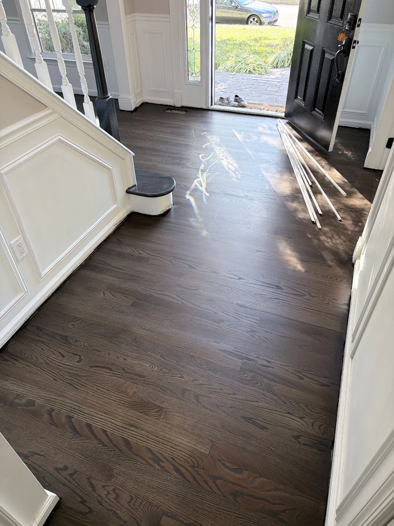 Entry with a newly refinished dark oak floor, front door open to the street